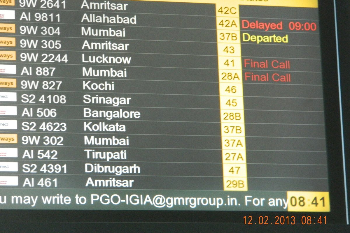 Electronic airport departure display board showing domestic flight cancellations and delays
