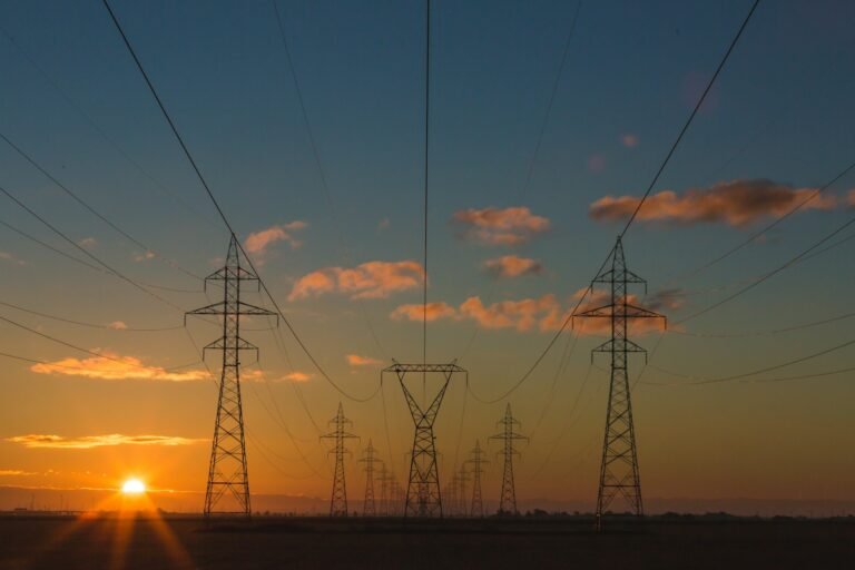 High-voltage electrical transmission towers and steel lattice infrastructure spanning a rural utility corridor