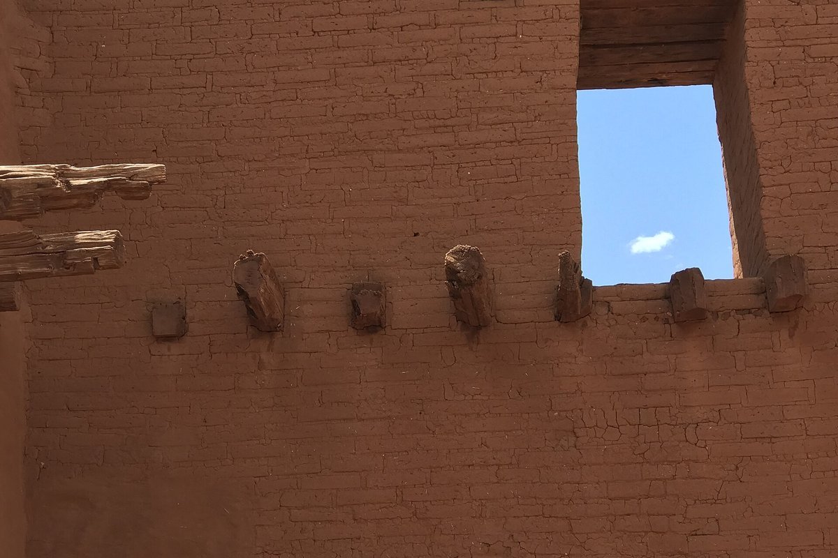 Earthen adobe wall featuring projecting wooden vigas and hand-smoothed contours characteristic of Santa Fe Style architecture
